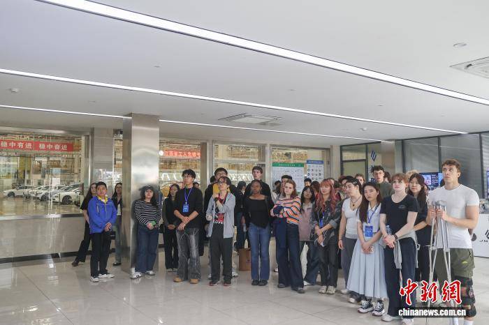中外青年学生在车间门口聆听介绍
